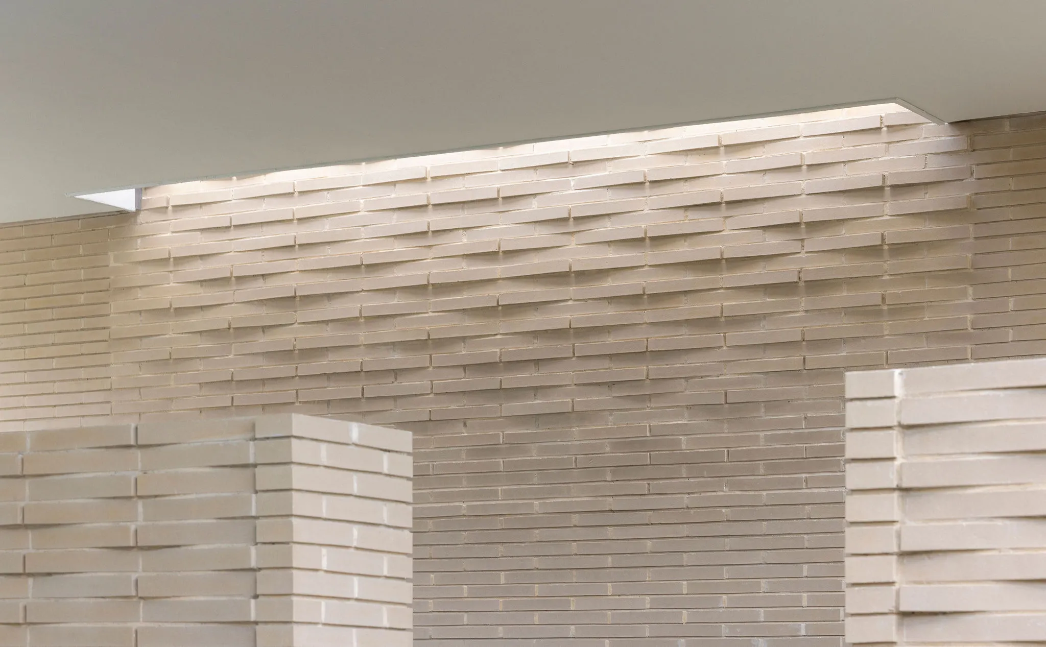 Detail of the woven brick wall washed by a concealed ceiling light