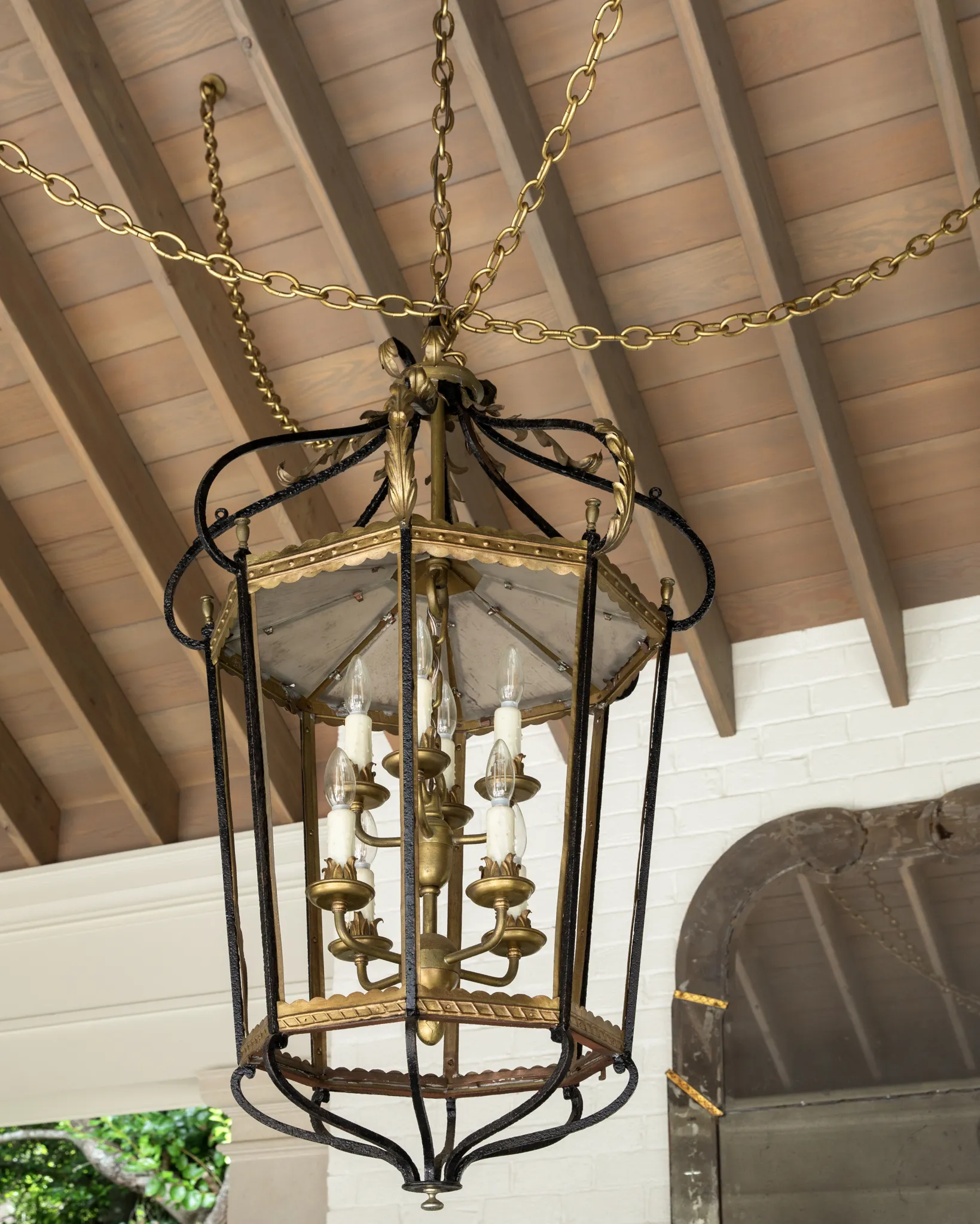 Iron and gilt lantern chandelier hung on chains from the wood-beamed ceiling