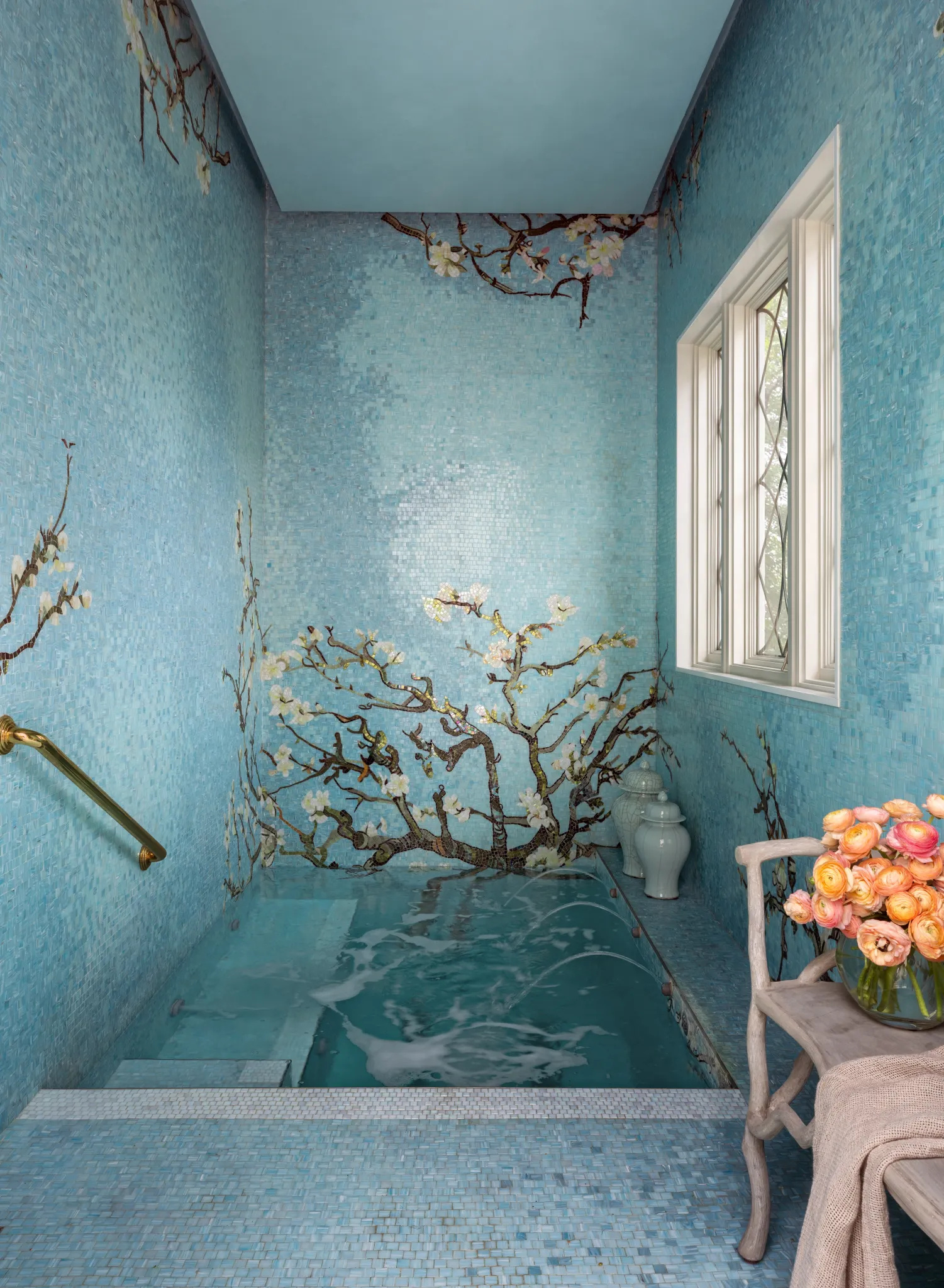 Plunge bath wrapped in blue glass mosaic with a blossoming branch motif