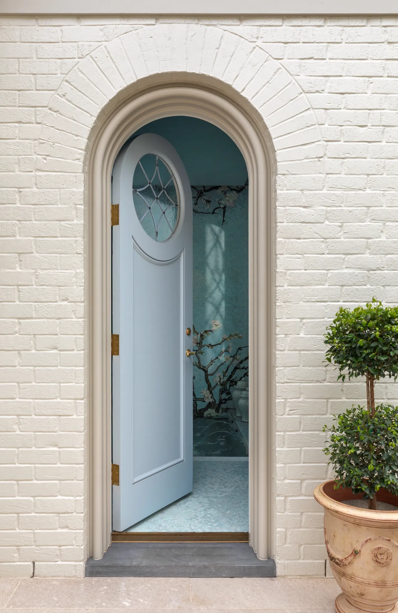 Arched blue door opening to the pool house's mosaic-tiled plunge bath